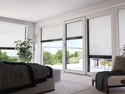modernes, helles Wohnzimmer mit vielen Fenstern, an denen hochwertige, helle Senkrechtmarkisen halb ausgefahren sind.