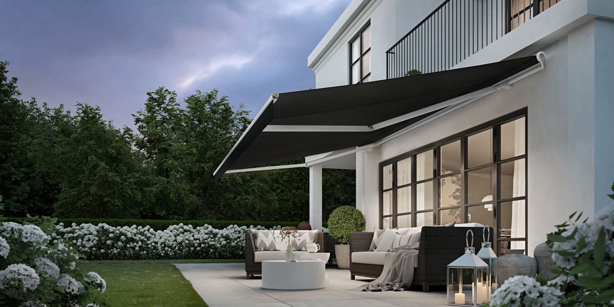 Weiße Stadtvilla mit weißer Markise markilux 1710 mit schwarzem Tuch, Licht in den Gelenkarmen und geradem Volant.