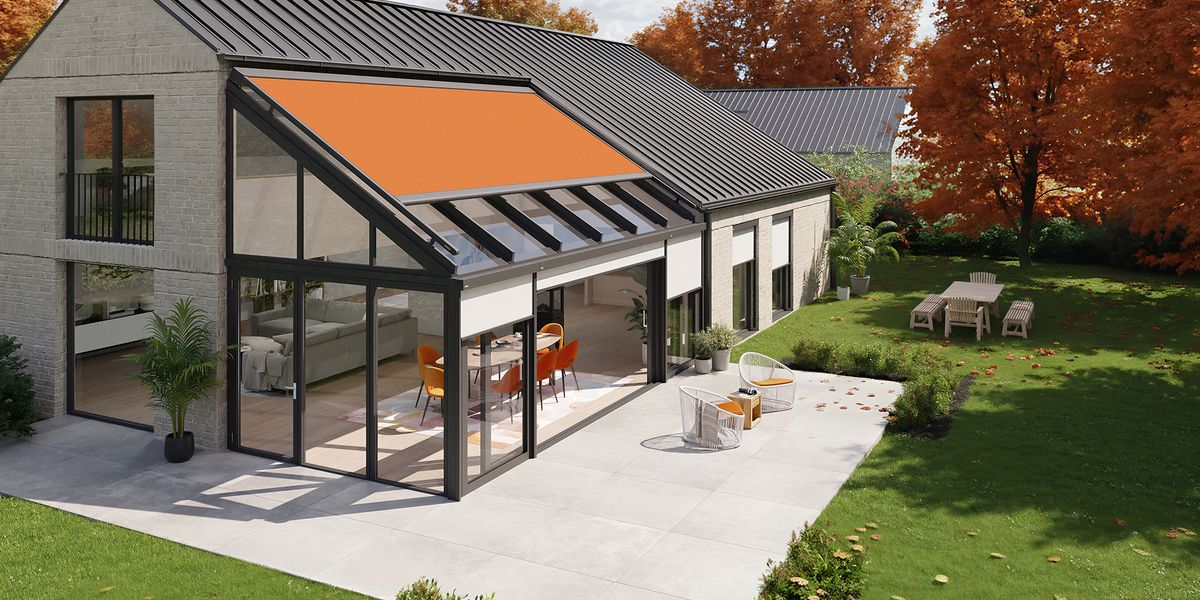 Modernes Einfamilienhaus mit einer Hausecke aus Fenstern, kombiniert mit Wintergartenmarkisen, in einer herbstlichen Umgebung.