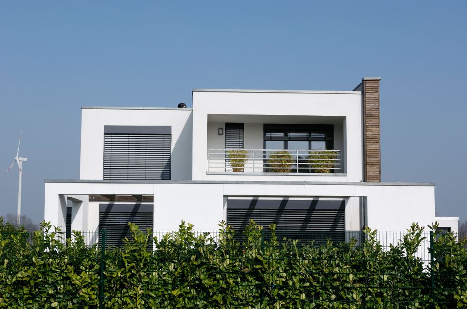 weißes modernes Haus im Cubus-Stil mit Raffstores an den Fenstern