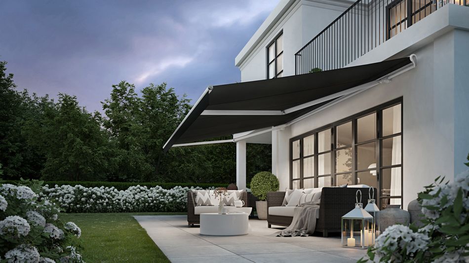 Weiße Stadtvilla mit weißer Markise markilux 1710 mit schwarzem Tuch, Licht in den Gelenkarmen und geradem Volant.