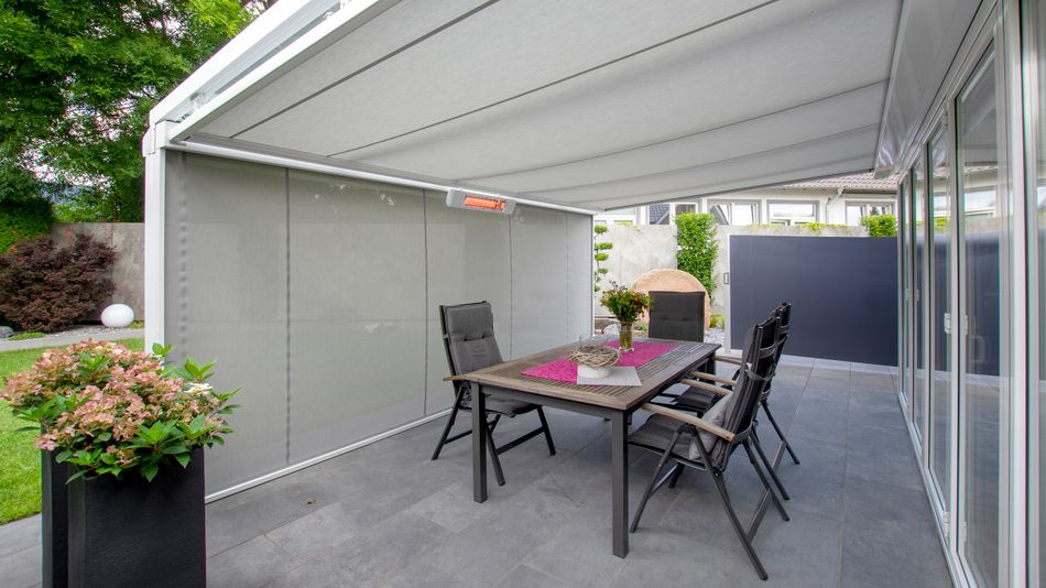 Weißes Terrassendach mit Unterglasmarkise markilux 779 mit weißem Gestell und grauem Tuch.