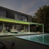 Pergolamarkise markilux style an einem modernen, schicken Kubusgebäude. Die grüne Beleuchtung der Pergola taucht die Terrasse und den Garten mit Pool in schönes Licht.